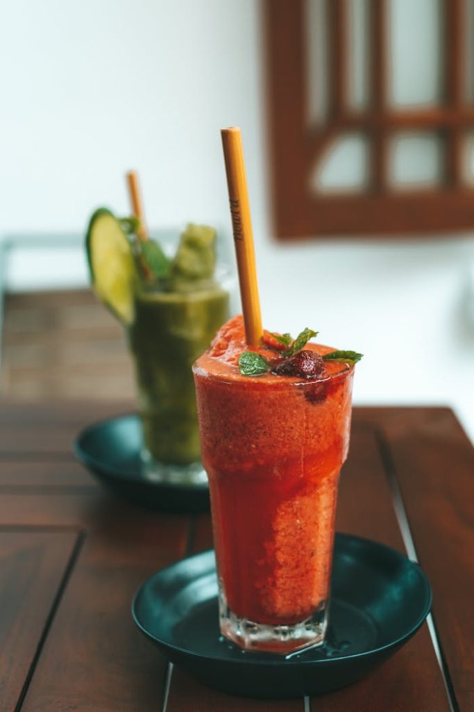 Refreshing fruit and vegetable smoothies garnished with mint leaves and served in glass cups outdoors.